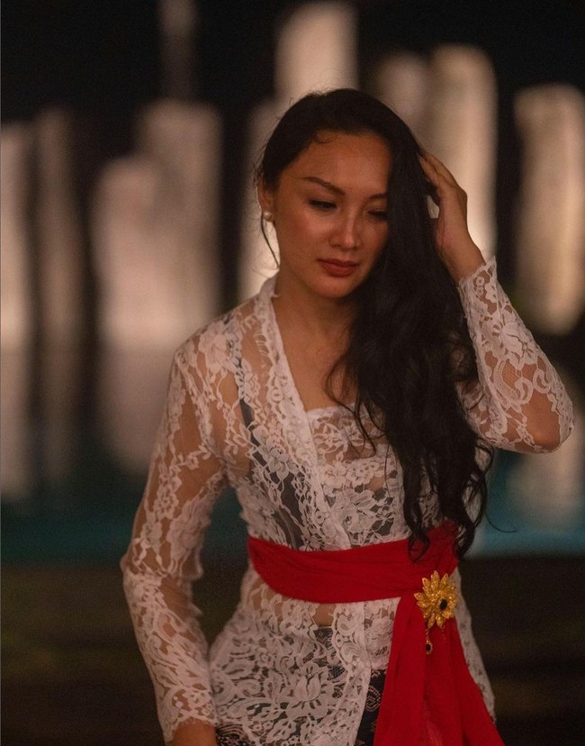 Tata Cahyani juga pernah memakai kebaya khas Bali. Kebaya lace warna putih dipadukan dengan dalaman hitam, serta dihias kain merah yang dililitkan pada bagian pinggang. Foto: Instagram/@tatacahyani
