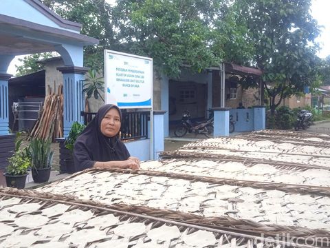 Herlina saat akan mengangkat rigen atau tatakan berisi opak karena cuaca mendung (Andika Syahputra/detikcom)