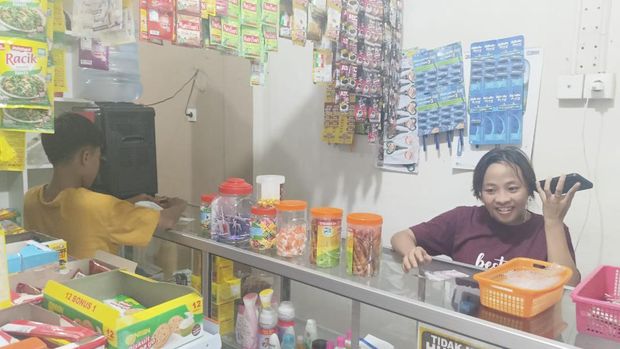 Pegawai Toko Anugrah, Siti Aisyah, saat berjaga , Selasa (23/4/2024). Warung Madura tersebut berlokasi di Jalan Trengguli, Penatih, Denpasar, Bali.
