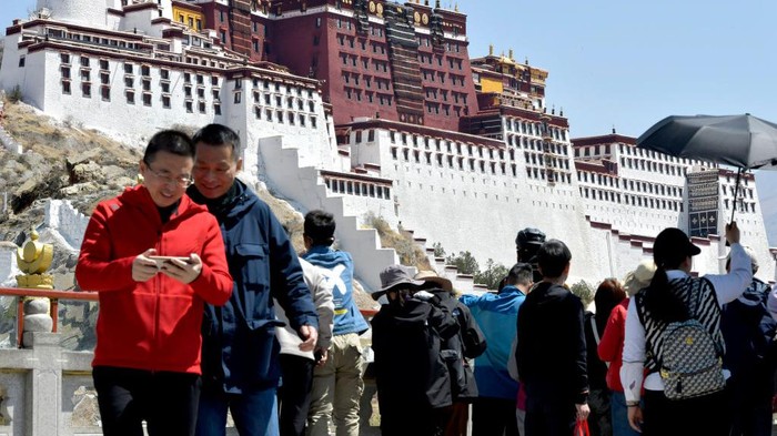 Turis mengunjungi alun-alun Kuil Jokhang di Lhasa, China. Sebagian dari mereka mengenakan kostum Tibet. Nih foto-fotonya.