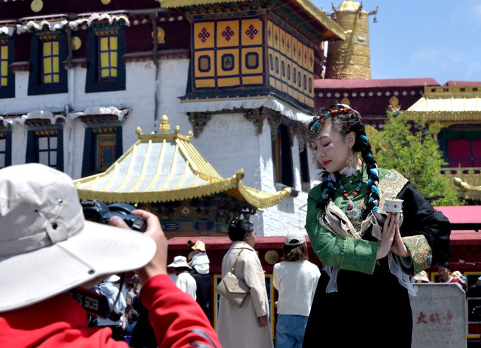 Turis mengunjungi alun-alun Kuil Jokhang di Lhasa, China. Sebagian dari mereka mengenakan kostum Tibet. Nih foto-fotonya.