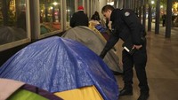 Seorang petugas polisi memeriksa tenda migran di kamp darurat, Selasa dini hari di Paris, Selasa (23/4/2024).