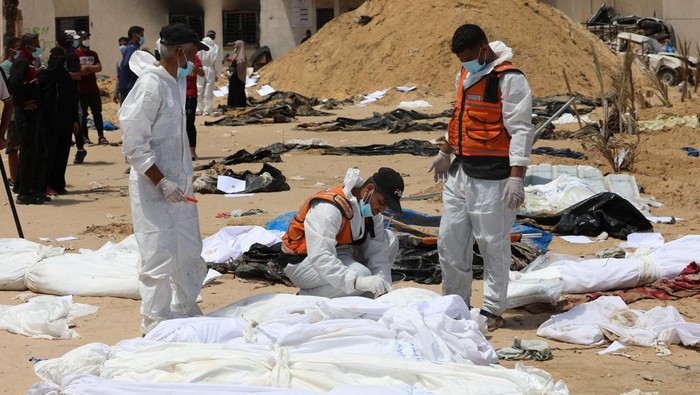 People work to move into a cemetery bodies of Palestinians killed during Israel's military offensive and buried at Nasser hospital, amid the ongoing conflict between Israel and the Palestinian Islamist group Hamas, in Khan Younis in the southern Gaza Strip, April 21, 2024. REUTERS/Ramadan Abed     TPX IMAGES OF THE DAY