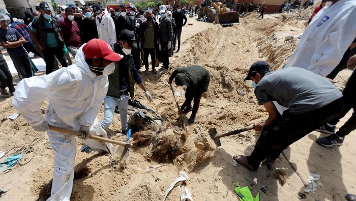 People work to move into a cemetery bodies of Palestinians killed during Israel's military offensive and buried at Nasser hospital, amid the ongoing conflict between Israel and the Palestinian Islamist group Hamas, in Khan Younis in the southern Gaza Strip, April 21, 2024. REUTERS/Ramadan Abed     TPX IMAGES OF THE DAY