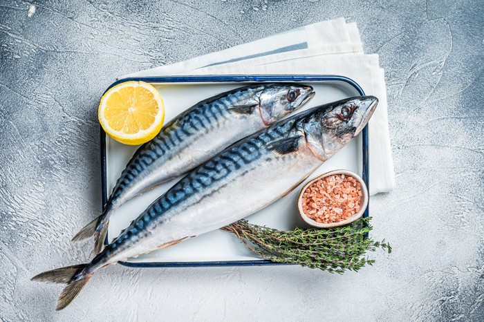 Raw mackerel scomber fish with ingredients for cooking in baking dish. White background. Top view.