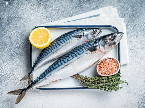 Raw mackerel scomber fish with ingredients for cooking in baking dish. White background. Top view.