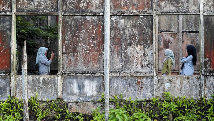 Warga berfoto di bagian dalam bangunan bekas benteng pertahanan yang terbengkalai di Kota Tua, kawasan Pasar Muara Tembesi, Batanghari, Jambi, Rabu (24/4/2024). Kota Tua Muara Tembesi merupakan salah satu kota tua di Provinsi Jambi yang telah ada sejak 1903 dan menyimpan beberapa bangunan bekas peninggalan masa kolonial Belanda namun terbengkalai dan beralih fungsi, di antaranya benteng pertahanan, rumah singgah Bung Hatta, dan Sekolah Rakyat. ANTARA FOTO/Wahdi Septiawan/wpa.