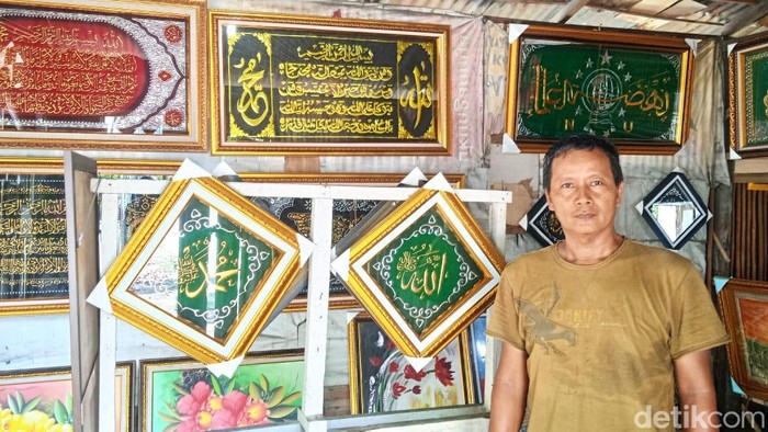 M Irwan menunjukkan produksi kaligrafi hasil karyanya (Andika Syahputra/detikcom)