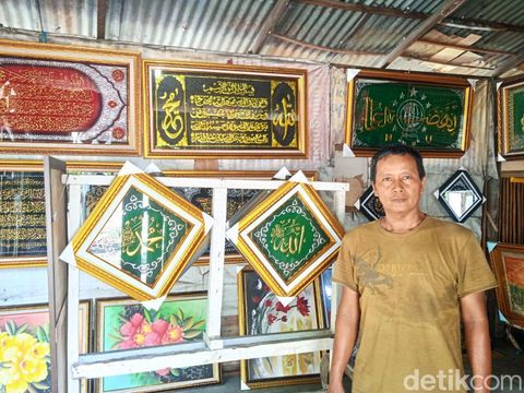 M Irwan menunjukkan produksi kaligrafi hasil karyanya (Andika Syahputra/detikcom)