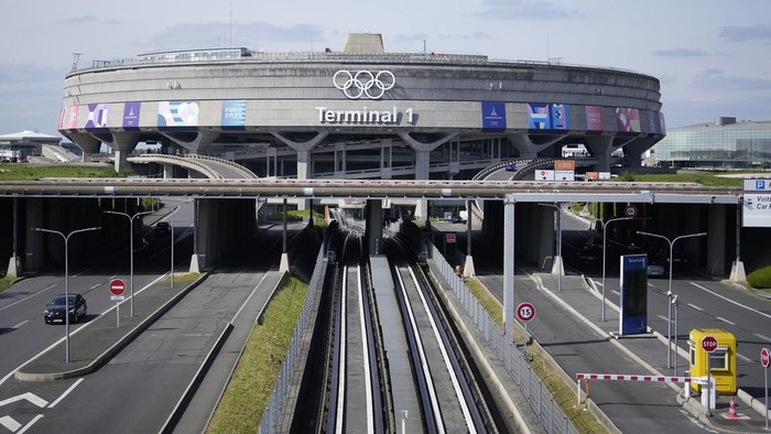 Paris Akan Jadi Zona Larangan Terbang Saat Upacara Pembukaan Olimpiade Gendarmes pose in front of the Charles de Gaulle airport, terminal 1, where the olympic rings were installed, in Roissy-en-France, north of Paris, Tuesday, April 23, 2024 in Paris. (AP Photo/Thibault Camus)