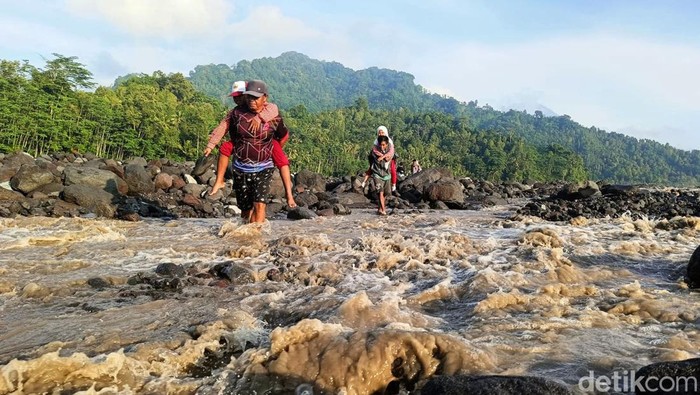 Sejumlah siswa harus digendong ayahnya menyebrangi Sungai Leprak, Desa Jugosari, Kecamatan Candipuro, Kabupaten Lumajang untuk berangkat ke sekolah di SDN Jugosari 03, Kamis 
(25/4/2024). Mereka harus menyebrangi sungai akibat jembatan limpas tertimbun material lahar dingin Semeru.