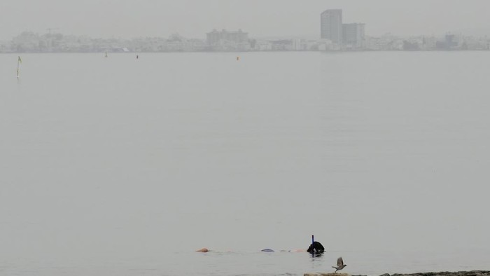 A man walks at the beach through a haze caused by dust, near southern coastal city of Larnaca, in the southeast Mediterranean island of Cyprus, on Thursday, April 25, 2024. A low-pressure system in North Africa is affecting the area with winds and dust. (AP Photo/Petros Karadjias)