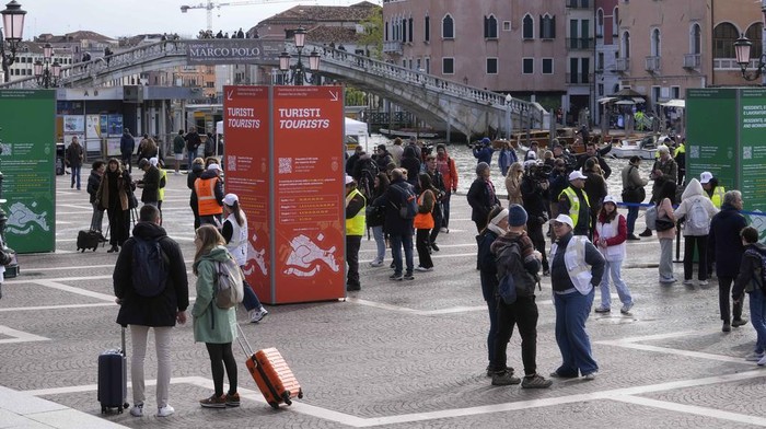 Suasana Venesia yang Mulai Terapkan Tiket Masuk untuk Wisatawan Tourists arrive at the main train station in Venice, Italy, Thursday, April 25, 2024. The fragile lagoon city of Venice begins a pilot program Thursday to charge daytrippers a 5 euro entry fee that authorities hope will discourage tourists from arriving on peak days. The daytripper tax is being tested on 29 days through July, mostly weekends and holidays starting with Italy's Liberation Day holiday Thursday. Officials expect some 10,000 people will pay the fee to access the city on the first day, downloading a QR code to prove their payment, while another 70,000 will receive exceptions, for example, because they work in Venice or live in the Veneto region. (AP Photo/Luca Bruno)