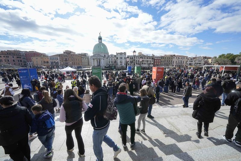 Tourists arrive at the main train station in Venice, Italy, Thursday, April 25, 2024. The fragile lagoon city of Venice begins a pilot program Thursday to charge daytrippers a 5 euro entry fee that authorities hope will discourage tourists from arriving on peak days. The daytripper tax is being tested on 29 days through July, mostly weekends and holidays starting with Italy's Liberation Day holiday Thursday. Officials expect some 10,000 people will pay the fee to access the city on the first day, downloading a QR code to prove their payment, while another 70,000 will receive exceptions, for example, because they work in Venice or live in the Veneto region. (AP Photo/Luca Bruno)