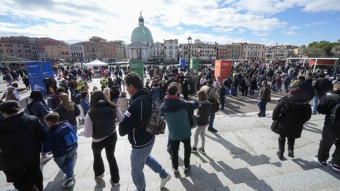 Suasana Venesia yang Mulai Terapkan Tiket Masuk untuk Wisatawan Tourists arrive at the main train station in Venice, Italy, Thursday, April 25, 2024. The fragile lagoon city of Venice begins a pilot program Thursday to charge daytrippers a 5 euro entry fee that authorities hope will discourage tourists from arriving on peak days. The daytripper tax is being tested on 29 days through July, mostly weekends and holidays starting with Italy's Liberation Day holiday Thursday. Officials expect some 10,000 people will pay the fee to access the city on the first day, downloading a QR code to prove their payment, while another 70,000 will receive exceptions, for example, because they work in Venice or live in the Veneto region. (AP Photo/Luca Bruno)