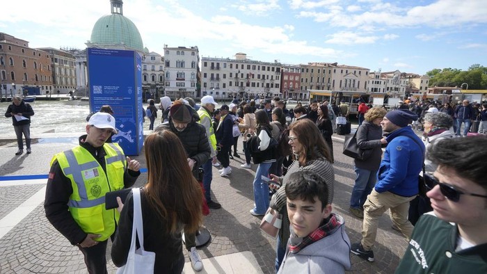 Suasana Venesia yang Mulai Terapkan Tiket Masuk untuk Wisatawan Tourists arrive at the main train station in Venice, Italy, Thursday, April 25, 2024. The fragile lagoon city of Venice begins a pilot program Thursday to charge daytrippers a 5 euro entry fee that authorities hope will discourage tourists from arriving on peak days. The daytripper tax is being tested on 29 days through July, mostly weekends and holidays starting with Italy's Liberation Day holiday Thursday. Officials expect some 10,000 people will pay the fee to access the city on the first day, downloading a QR code to prove their payment, while another 70,000 will receive exceptions, for example, because they work in Venice or live in the Veneto region. (AP Photo/Luca Bruno)
