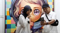 Pengunjung berswafoto dengan latar belakang karya seni yang dipamerkan.