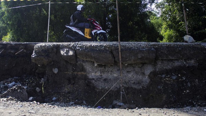 Pengendara motor melintas di sebelah jalan yang amblas di Jalan Raya Loji, Wanasari, Telukjambe Barat, Kabupaten Karawang, Jawa Barat, Jumat (26/4/2024). Jalan yang menghubungkan Karawang dan Kabupaten Bekasi tersebut amblas sehingga untuk kendaraan roda empat harus menggunakan sistem buka tutup. ANTARA FOTO/Robby Hamzah/wpa/Spt.