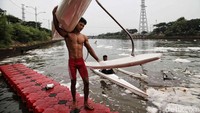 Seorang atlet memanggul perahu dayung usai menjalani latihan di sungai kotor tersebut. 