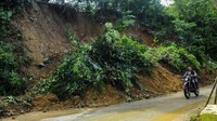 Hujan deras mengakibatkan tebing setinggi 20 meter longsor menimbun jalan dan membahayakan pengendara yang melintas.
