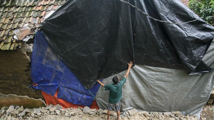 Rumah terdampak gempa Garut di Bandung Barat Warga menutup tembok rumah yang roboh akibat terdampak gempa dengan menggunakan terpal di Cipatat, Kabupaten Bandung Barat, Minggu (28/4/2024). Dua unit rumah di Bandung Barat mengalami rusak akibat terdampak gempa berkekuatan 6,5 skala magnitudo yang mengguncang Kabupaten Garut pada Sabtu (27/4). ANTARA FOTO/Novrian Arbi/tom.