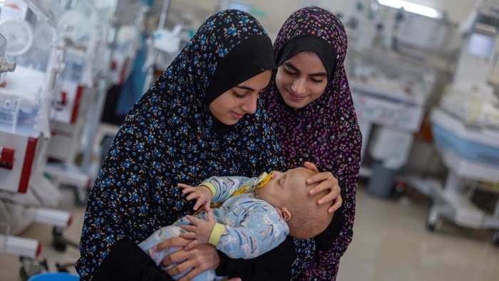 Alaa Abu Al-Roos and her sister look after Yehia Hamuda, a Palestinian infant, who was evacuated to south Gaza as a premature baby after Israeli forces raided Kamal Adwan hospital in northern Gaza Strip and is currently separated from his parents due to an Israeli checkpoint that separates north Gaza from the south, at Al-Emirati hospital, in Rafah in the southern Gaza Strip, April 24, 2024. REUTERS/Mohammed Salem