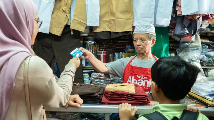 Dukung UMKM Lewat Layanan Digital Pedagang pakaian yang juga Agen JakOne Abank tengah melayani pembeli yang menggunakan transaksi dengan Kartu Jakarta Pintar Plus di Pasar Santa, Jakarta Selatan (30/4).