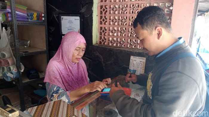 Kardiana saat mencoba EDC untuk transaksi BRIZZI yang dipandu PPBK BRILink Abel Fabyan di Toko Pendowo