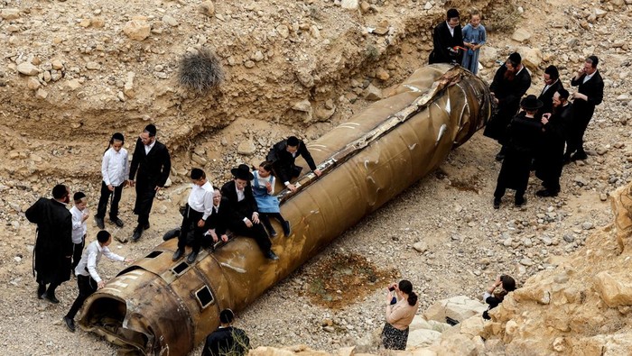 Ultra Orthodox Jews hang around apparent remains of a ballistic missile before it has been evacuated from the location it was found lying in the desert, following a massive missile and drone attack by Iran on Israel, near the southern city of Arad, Israel April 26, 2024. REUTERS/Amir Cohen     TPX IMAGES OF THE DAY