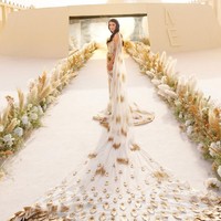 Meskipun dekorasi pernikahan minimalis, sang mempelai wanita, Erika Hammond, tampil megah dalam balutan gaun bergaya ekstravaganza. Wanita 33 tahun ini mengenakan gaun pengantin rancangan Rahul Mishra. Gaun transparan berbahan tulle dihiasi ornamen emas, serta dilengkapi selendang yang memanjang dengan motif dedaunan menambah kesan dramatis. Foto: Instagram/@erikaannhammond @bottega53