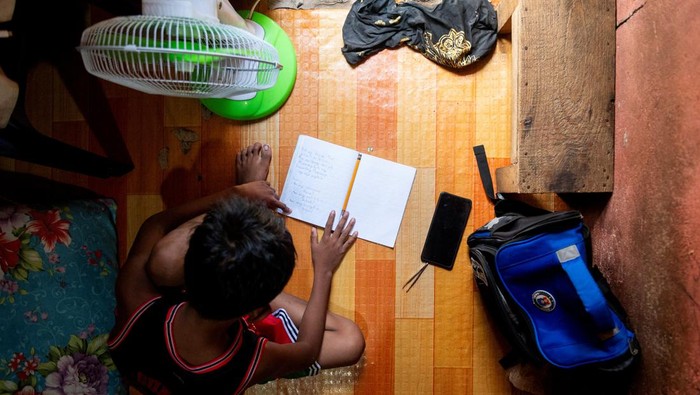 A student answers his learning module following the suspension of in-person classes, inside his house in Manila, Philippines, April 26, 2024. REUTERS/Lisa Marie David