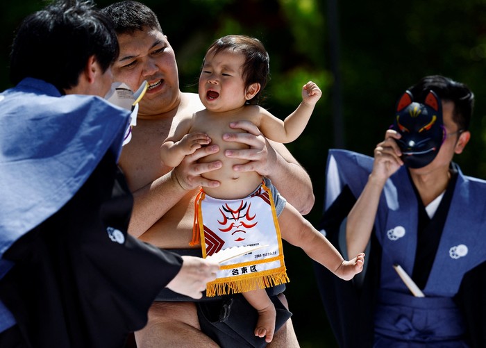 Amateur sumo wrestlers hold babies during Nakizumo or a baby-crying sumo contest, where two wrestlers hold a baby each and a referee makes faces and loud noises to make them cry and determine the winner based on the loudest baby, at Sensoji temple in Tokyo, Japan, April 28, 2024. The ritual is believed to aid the healthy growth of the children and ward off evil spirits. REUTERS/Issei Kato     TPX IMAGES OF THE DAY