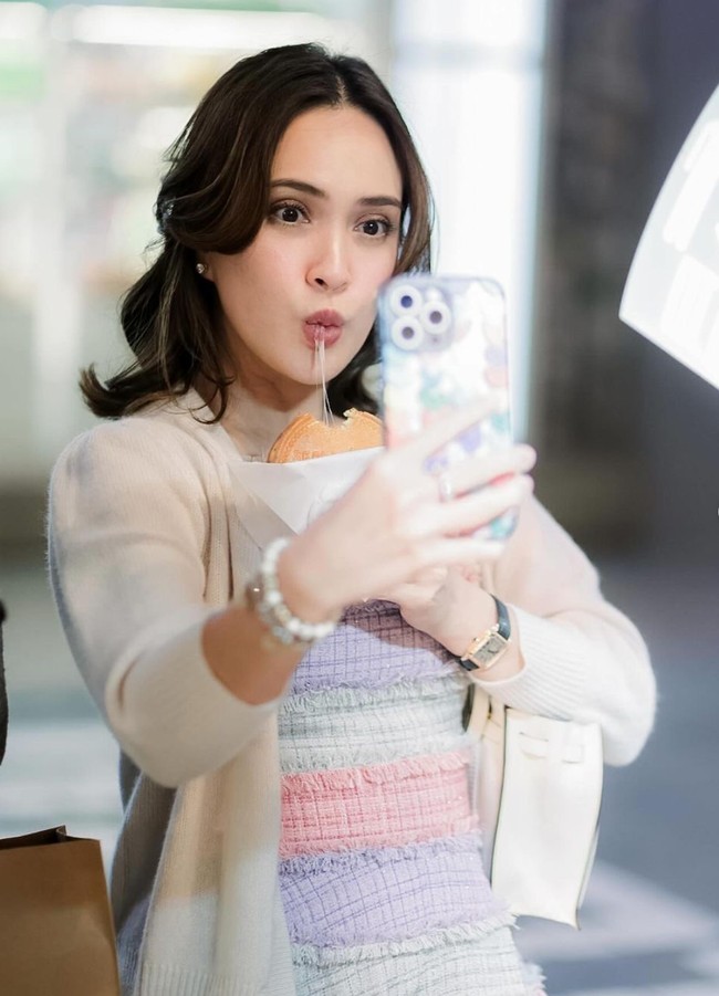 Mengenakan riasan minimalis, Shandy tampak mencatok rambut pendeknya dan mengikatnya setengah. Ia ber-selfie sambil memamerkan makanan yang dipegangnya. Foto: Instagram/@shandyaulia