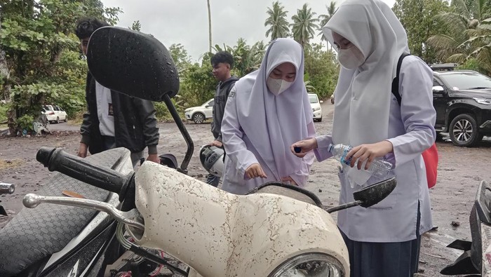 Siswi mengenakan masker sambil melihat abu vulkanik yang mengenai sepeda motornya di Manado, Sulawesi Utara, Selasa (30/4/2024). Dampak material erupsi gunung Ruang di kabupaten Kepulauan Sitaro pada Selasa (30/4) dinihari, telah mencapai kota Manado yang mengakibatkan timbunan abu vulkanik setebal setengah centimeter sehingga sejumlah sekolah terpaksa memulangkan lebih awal siswanya. ANTARA FOTO/Yudi Makka/adw/YU