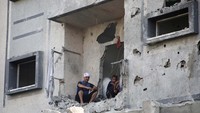 Sejumlah warga Palestina duduk di sebuah bangunan yang ikut rusak akibat rudal Israel.