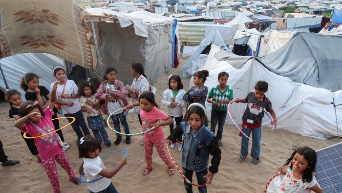 Palestinian children play with hula hoops near makeshift tent camp as schools remain closed due to Israel's military offensive, amid the ongoing conflict between Israel and the Palestinian Islamist group Hamas, in Deir Al-Balah in the central Gaza Strip April 28, 2024. REUTERS/Ramadan Abed