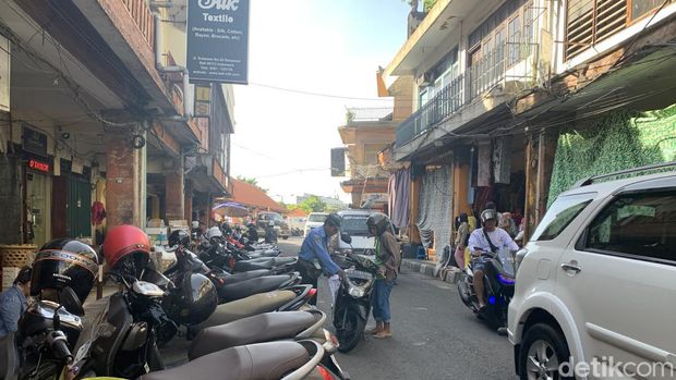 Potret juru parkir Made Sujana saat membantu mengeluarkan motor warga di Jalan Sulawesi.