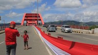 Warga berswafoto di dekat Bendera Merah Putih yang terbentangan di Jembatan Youtefa Holtekamp, Kota Jayapura, Papua, Rabu (1/5/2024).