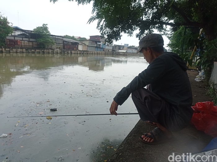 Asep mancing di kali dekat RTH Tubagus Angke, Jakarta Barat, pernah dapat kondom. (Taufiq Syarifudin/detikcom)