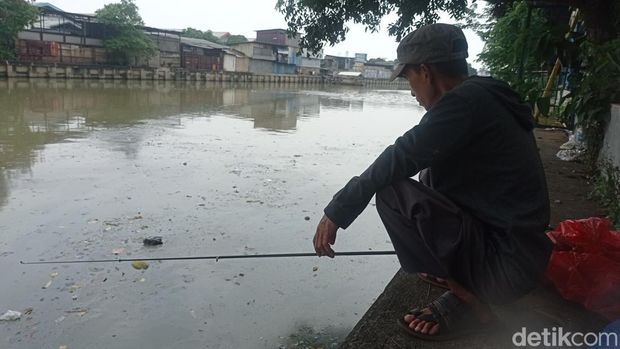 Asep mancing di kali dekat RTH Tubagus Angke, Jakarta Barat, pernah dapat kondom. (Taufiq Syarifudin/detikcom)