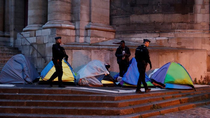 French Gendarmes walk past migrant tents during the evacuation of the camp on Place Saint-Gervais near Paris City Hall, France, April 30, 2024. REUTERS/Abdul Saboor