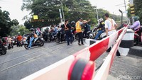 Meski palang pintu perlintasan kereta telah tertutup, pemotor masih nekat melintas.  