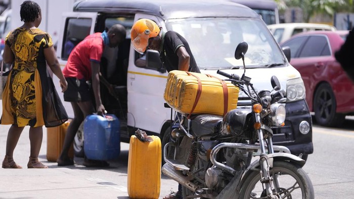 A woman carries jerrycans as she walks past cars waiting in a queue to buy fuel at a petrol station in Lagos, Nigeria Tuesday, April 30, 2024. Nigerians were queuing for hours to buy fuel across major cities on Tuesday as the West African nation faced its latest fuel shortage, resulting in increased hardship for millions already struggling with the country's economic crisis. (AP Photo/Sunday Alamba)