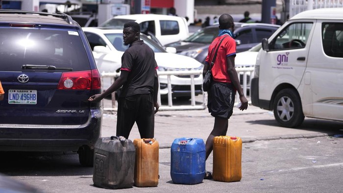 Situasi Nigeria Saat BBM Langka A woman carries jerrycans as she walks past cars waiting in a queue to buy fuel at a petrol station in Lagos, Nigeria Tuesday, April 30, 2024. Nigerians were queuing for hours to buy fuel across major cities on Tuesday as the West African nation faced its latest fuel shortage, resulting in increased hardship for millions already struggling with the country's economic crisis. (AP Photo/Sunday Alamba)