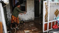 Seorang warga terlihat membersihkan lumpur sisa banjir di teras rumanhnya.  