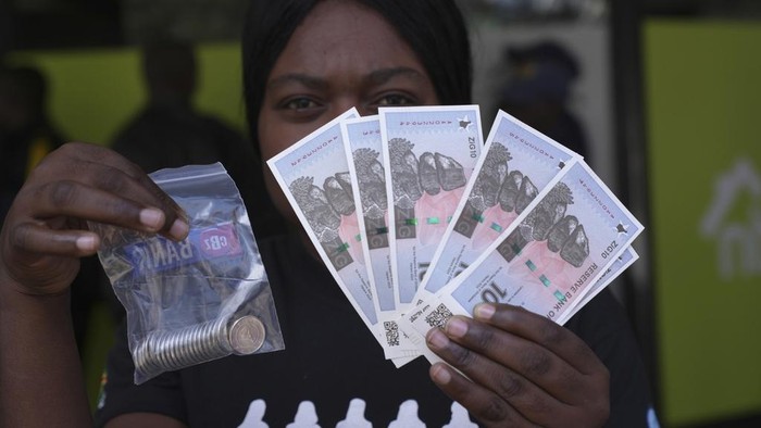 A woman holds the new Zimbabwean banknotes and coins called the ZiG, in the streets of Harare, Zimbabwe, Tuesday, April 30, 2024. Zimbabwe started circulating banknotes and coins for another new currency Tuesday in its latest attempt to solve a long-running and at times baffling monetary crisis that has seen the government try gold coins and a digital currency among other ideas. (AP Photo/Tsvangirayi Mukwazhi)
