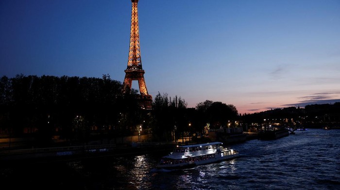 A tourist boat travels on the River Seine near the Alma bridge with the Eiffel Tower in the background at night in Paris, France, April 18, 2024. REUTERS/Benoit Tessier