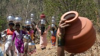 Sejumlah warga berjalan sembari membawa pot ke sumur yang ada di Kasara, India, Rabu (1/5/2024).