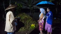 Tiga orang warga menunggu kerabatnya dievakuasi dari rumah yang terendam banjir.