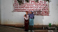 Nana, pelajar kelas 4 SD berpose bersama ibunya di depan spanduk keluh kesah warga.   